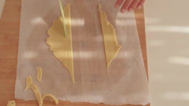 Ellerin yakın çekimi hamuru tahta bir tahtanın şeritlerine ayırır..