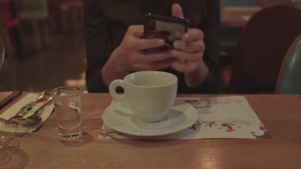 Використання телефону в руках дівчини в руках після пиття кави — стокове відео