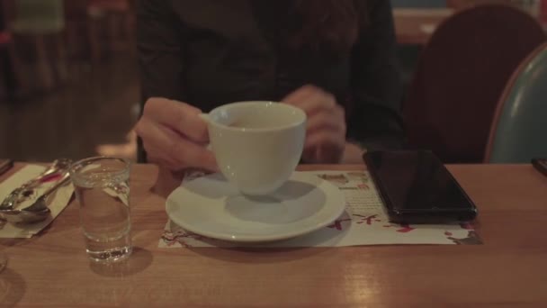 ガールハンドはドリンクカフェテーブルでマグカップを上げます。彼女はコップ一杯の水を飲んで. — ストック動画