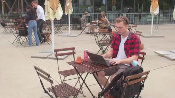 Estudiante utiliza el ordenador portátil mientras está sentado en la cafetería de la calle Uso de Internet público — Vídeo de stock