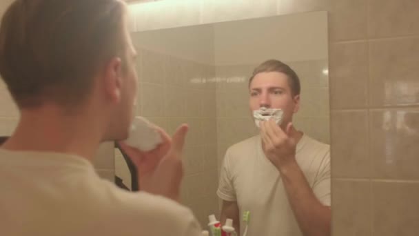 Man applies shaving foam face. He rubs hand over abacus, preparing skin shaving. — стоковое видео