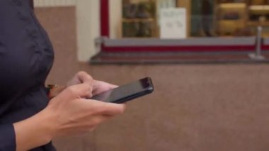 Hareket halindeki bir kızın elinde telefonu kullanmak. Ekrana tıklıyor..