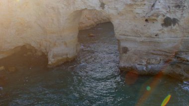 Deniz suyundaki taş kemer. Güneş ışığı dikkat çeker. Doğal pürüzlülük.