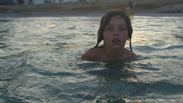 Портрет дитини, що плаває в морі біля берега ввечері на заході сонця . — стокове фото
