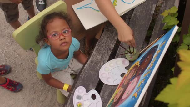 Seorang anak berbakat dengan palet, kanvas dan kuas menyelesaikan lukisan. — Stok Video