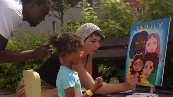 Чорний чоловік і біла жінка з дівчиною малюють сімейний портрет відкритий . — стокове відео