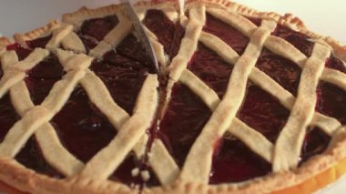A close-up of a traditional Italian pie being cut into portions with a knife..