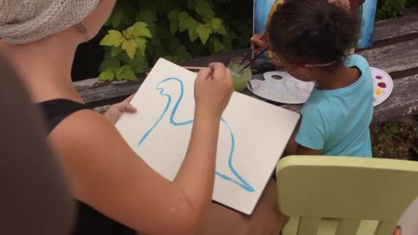 Måleri verkstad för barn. Läraren ritar en dinosaurie under det fria. — Stockvideo