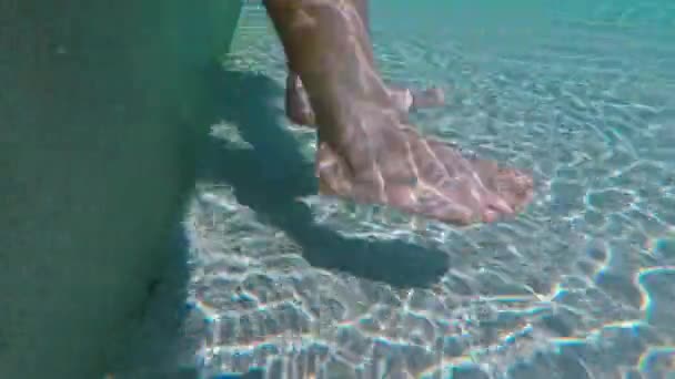 Dangling legs underwater in the pool, sun glare at the bottom. Summer time. — Stock video