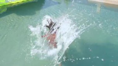Child jumps into pool, splashes, swims underwater. Confidence booster for kids.