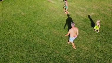 Man with children plays ball on lawn during the summer holidays. Active pastime.