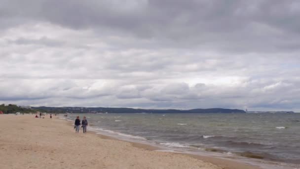 Shore beach with strollers. Sandy sea coast in autumn, beautiful clouds in sky — Stockvideo