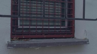 Prison window with metal bars and grate. Building exterior element.