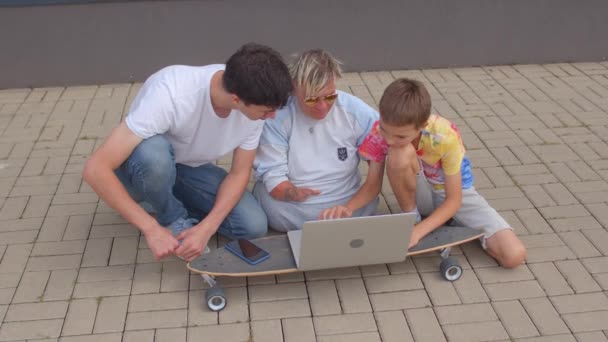 Usando laptop no longboard enquanto sentado calçada. Comunicação moderna de jovens — Vídeo de Stock