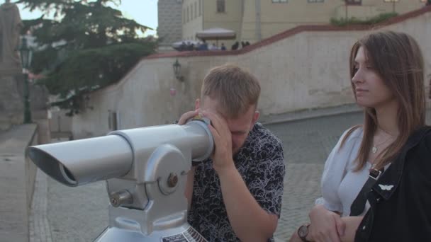 Utilisation de jumelles touristiques panorama ville. Il regarde à travers l'oculaire, elle attend. — Video