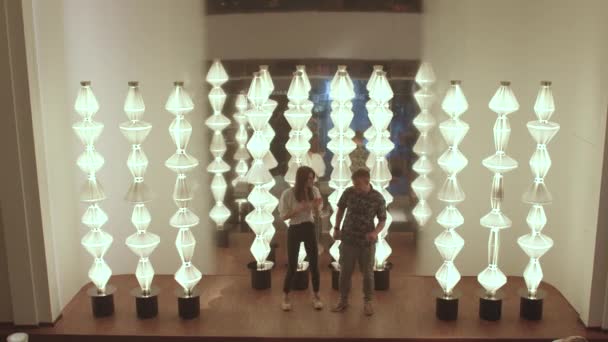 A man and a woman are doing a dance against backdrop of bright lamps — Stock Video