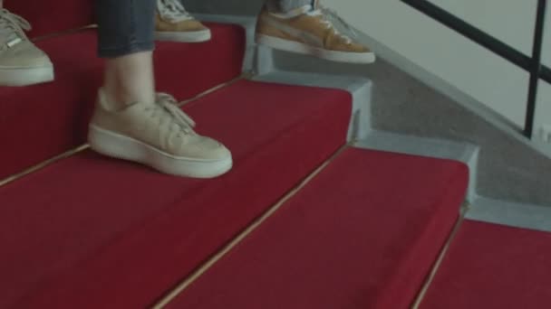 階段を上る足の動き。赤いカーペットは角に固定されています. — ストック動画