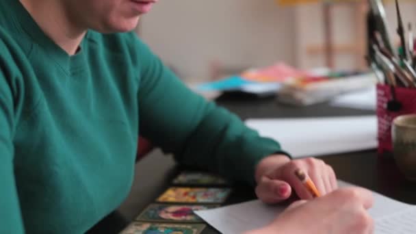 Mujer escribe texto con un lápiz en papel. Está enfocada. Mira la sábana.. — Vídeos de Stock