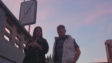 Siluet çift merdivenlerden aşağı iniyor. Pembe bir gökyüzünün arka planında.
