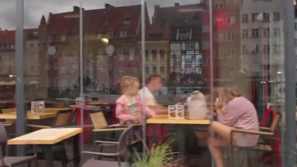 Europejscy mieszkańcy miast jedzą przy stolikach w werandach kawiarni. — Wideo stockowe