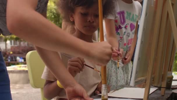 Szabadtéri festészet tanfolyam gyerekeknek. A gyerekek festékkel festenek a szabadban.. — Stock videók