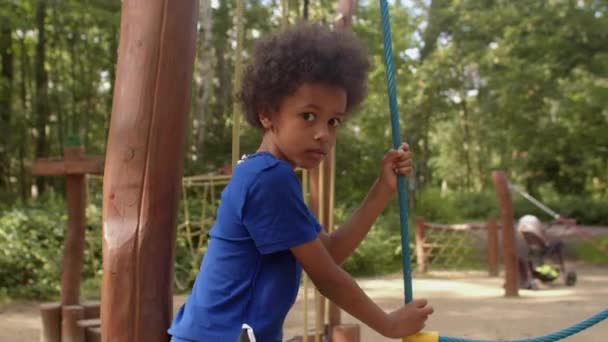 Retrato de un chico afroamericano supera un obstáculo de cuerda, mira a la cámara. — Vídeo de stock