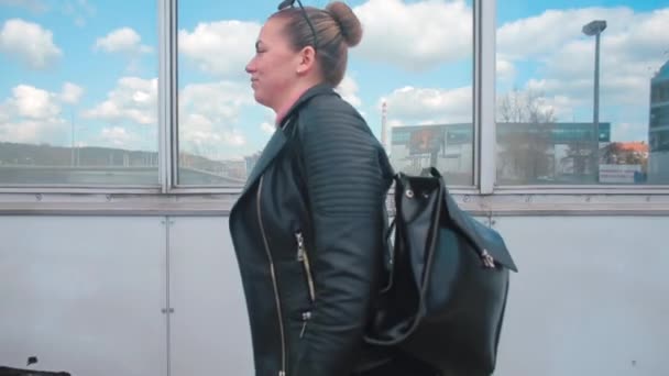 Kobieta zbliża się do szyby w mieście. Ma plecak na ramieniu.. — Wideo stockowe