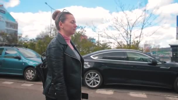 Femme met lunettes yeux temps ensoleillé. Elle se déplace à travers la ville de stationnement. — Video