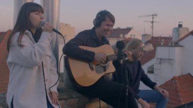 Evin çatısında canlı akustik konser. Mikrofon ve gitarı kullanarak.
