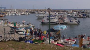 Yatın kıyısındaki balık pazarı park eden adam ağı çözüyor..