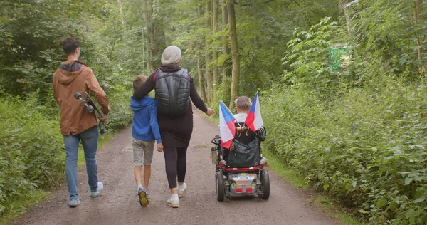 Rodinný handicapovaný člověk se pohybuje lesem park učinit kroky kočár role — Stock fotografie