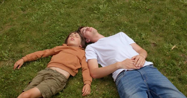 Odpočívající dítě a učitelka. Denní venkovní spánek a relaxace na trávě. — Stock fotografie