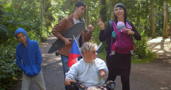 Szczęśliwa osoba z niepełnosprawnością na wózku inwalidzkim z czeskimi flagami, tańczący przyjaciele. — Zdjęcie stockowe