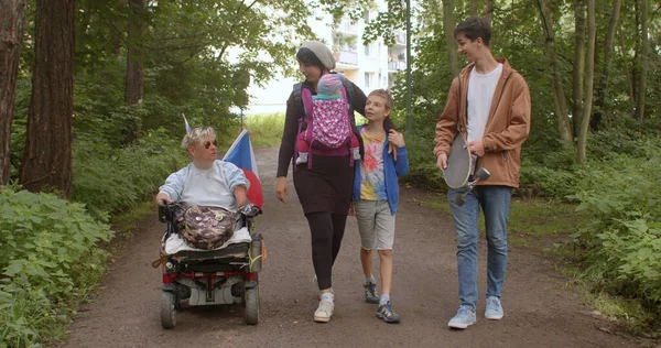 Handikappad familjemedlem går i rullstol i parken. Tid tillsammans — Stockfoto