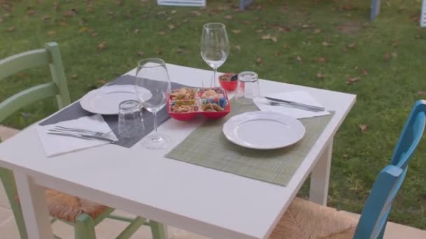 Stůl pro dva bez lidí. Svačinka na talířích, prázdné sklenice na víno. Spouštěč. — Stock video