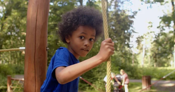 Portrait of an African American boy overcomes a rope obstacle, looks at camera. — Stockfoto