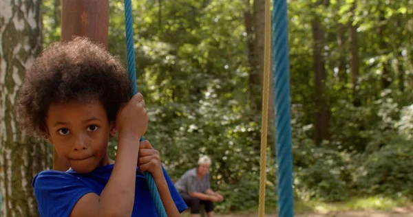 Portret van een Afro-Amerikaanse jongen overwint een touw obstakel, kijkt naar camera. — Stockfoto