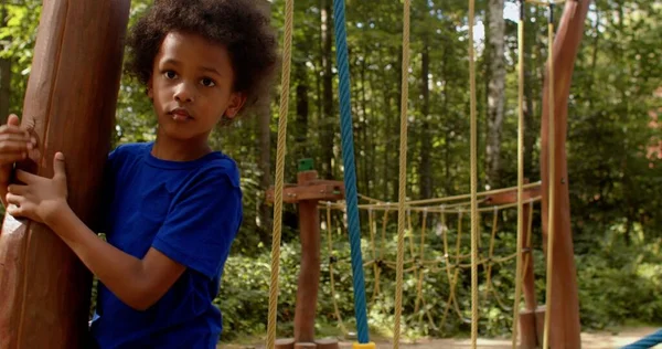 Pojken rör sig skickligt längs den gångjärnsförsedda repstigen på lekplatsen, tar tag i repen — Stockfoto