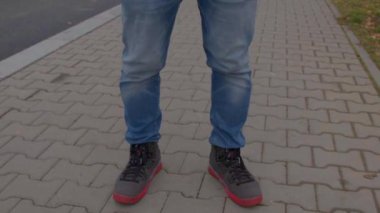 Kaldırımda duran bir adamın tam boy portresi. Kameraya bakıyor..