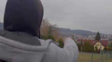 Kapüşonlu adam şehri gösteriyor. Hareket yönünü gösterir..