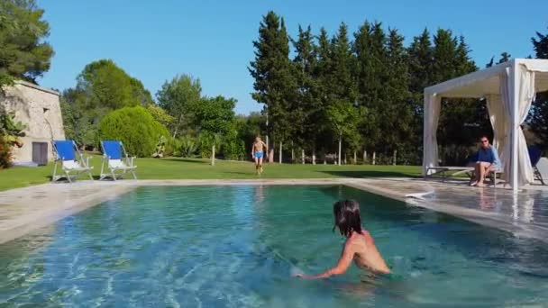Dwóch chłopców bawiących się w basenie z niebieską wodą. Zajęcia rekreacyjne w upalny dzień. — Wideo stockowe