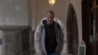 Şehrin kemerlerinde bir adam hareket ediyor. Eller cepte, sırt çantası omuzda..