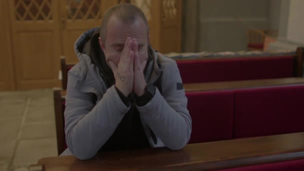 Muž sedí v kostele. Modlí se. Drží ruce u obličeje. — Stock video