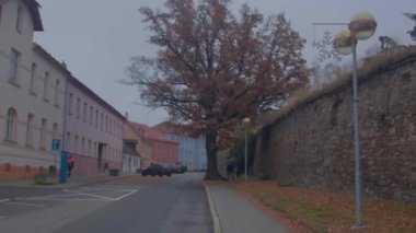 Şehir caddesi boyunca kamera hareketleri. Küçük bir kasabada boş bir araba park ediyor.