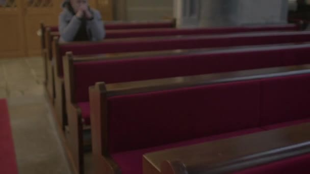 Ein Mann betet auf einer Bank in einer Kirche. Er hält den Kopf, er spricht über Sünden. — Stockvideo