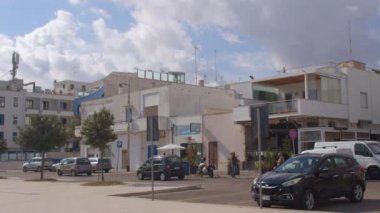 Yol kenarındaki güney binalarının cepheleri. Arabalar park halinde, bulutlu gökyüzü