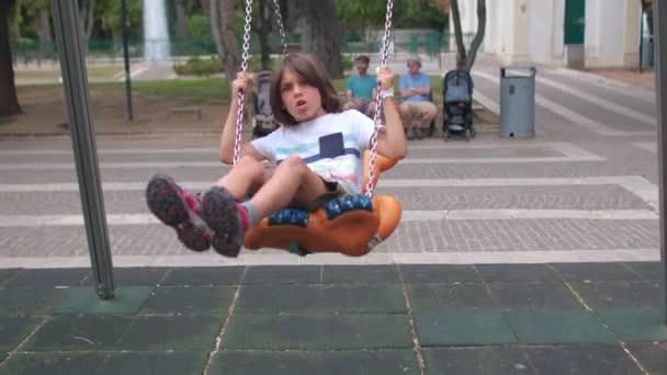 Vrijetijdsactiviteiten in het park. Jongen spelen in de stedelijke speeltuin, swing. — Stockvideo