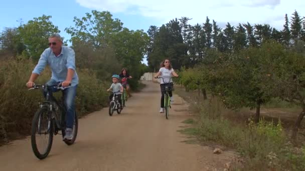 Die Familie radelt auf der Straße im Dorf, der Radfahrer ist ihnen voraus.