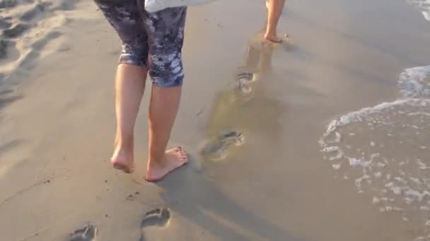 Bare feet leave footprints on sandy beach man moves on walk along seashore. — Stockvideo