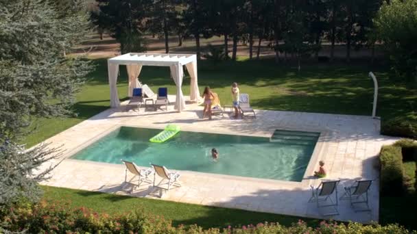 Παιδί πηδά σε εξωτερική πισίνα, κολυμπά με την επίβλεψη των γονέων ηλιοθεραπεία. — Αρχείο Βίντεο